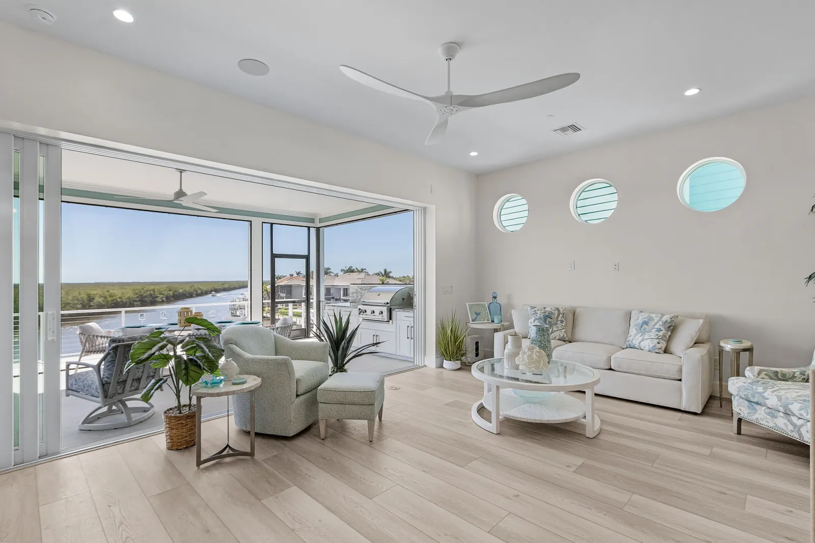 Living room porthole windows lanai view at Pelican's Perch, a custom home built by Marvin Homes in Cape Coral, Florida